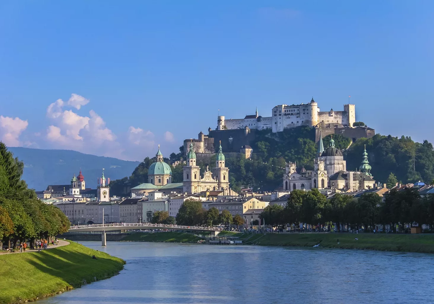 Salzburg in summer seen from one of the bridges on River Salzach. On the top of the rocky hill stands the imposing Hohensalzburg Fortress, built in 1077. The city is renowned for its baroque architecture and has been listed in UNESCO World Heritage Site in 1996. Salzburg, Austria.